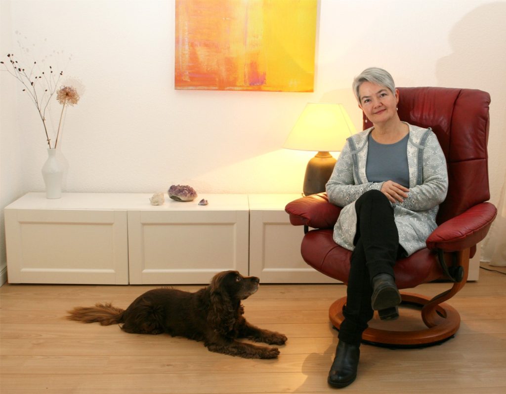 Dr. med. Uta Erle sitzt im Behandlungsraum mit Therapiehündin Nala, dem Cocker Spaniel