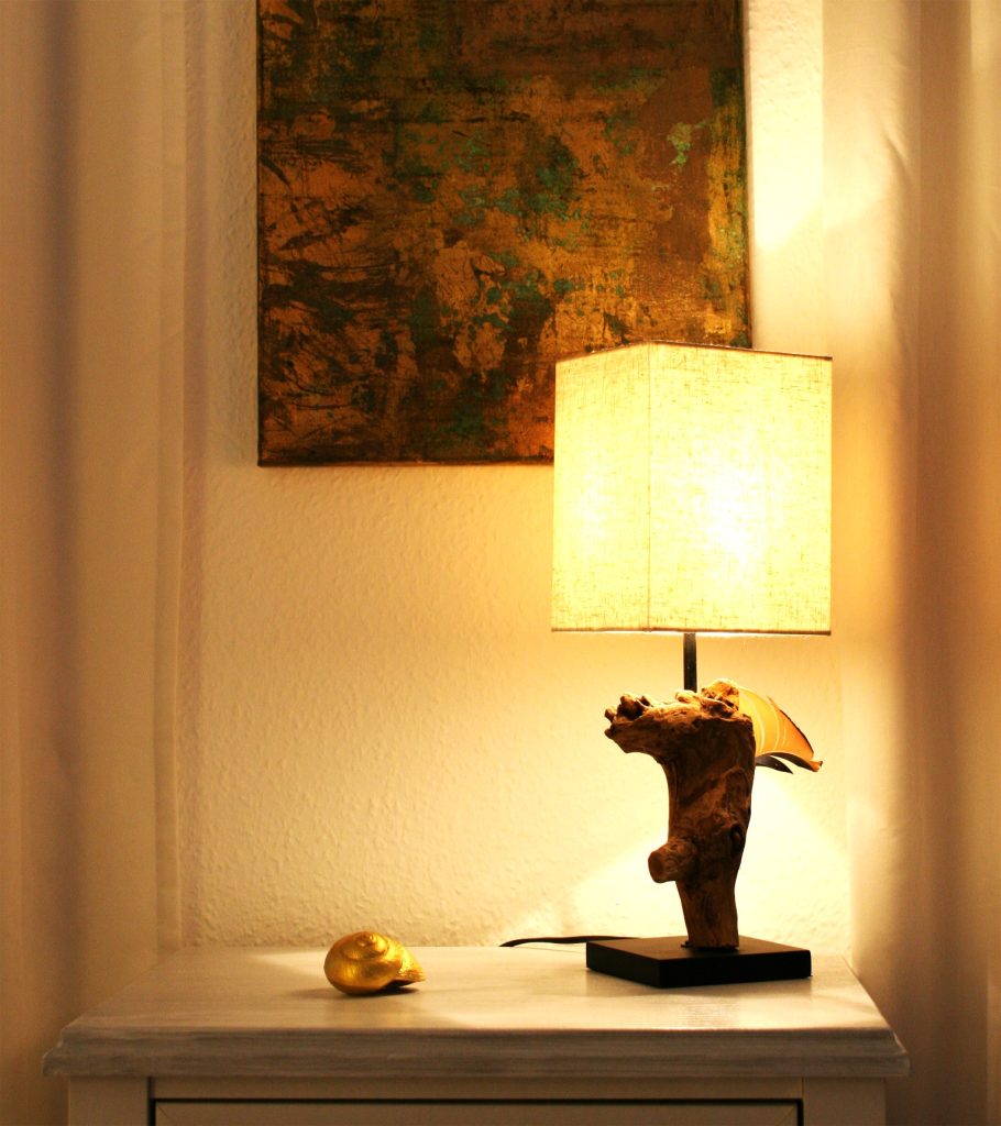 Stilleben mit Tischlampe mit Holzfuss und vergoldeter Weinbergschnecke